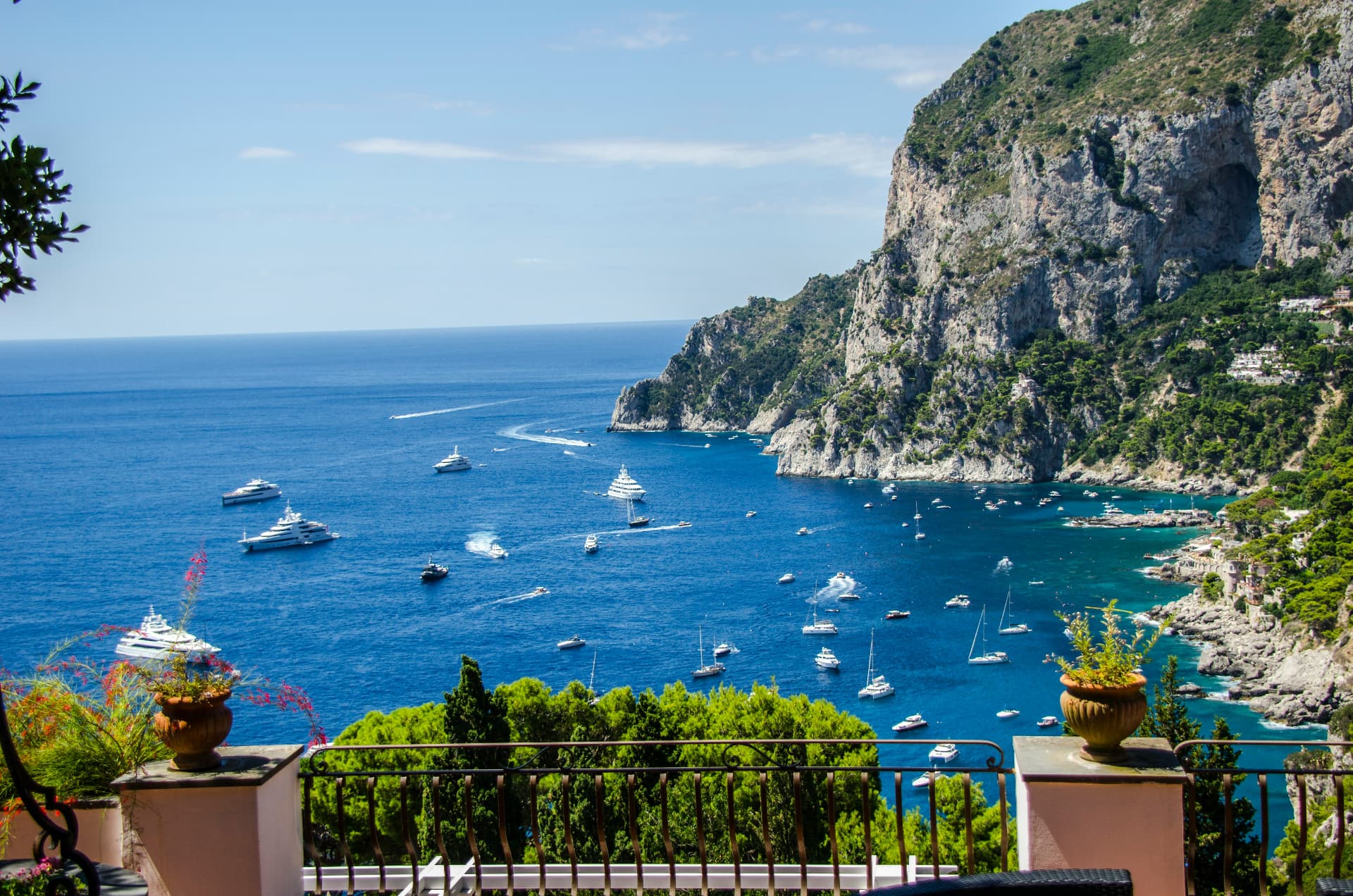 Terrace view over the Amalfi Coast with yachts anchored in deep blue water below cliffs