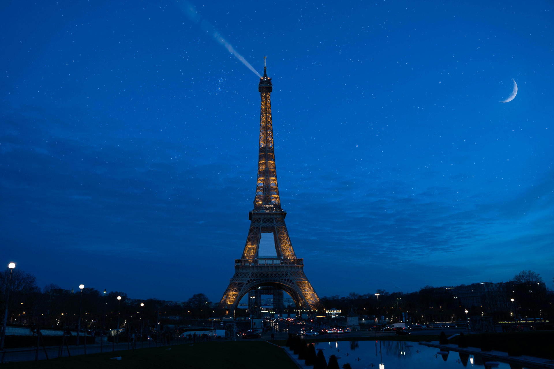 The Eiffel Tower soaring between classic Parisian apartment buildings and autumn trees beneath a bright blue sky