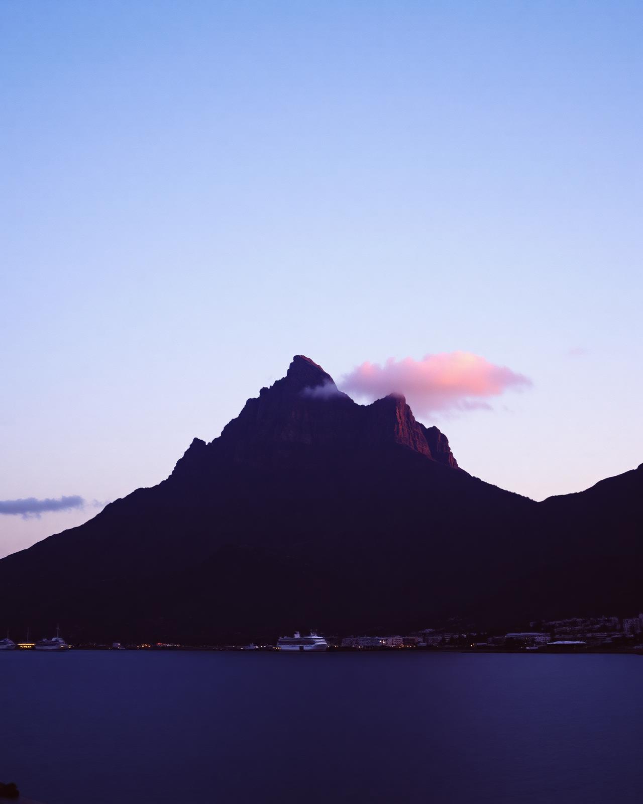 Table Mountain rising above Cape Town at dusk with the waterfront city lights below